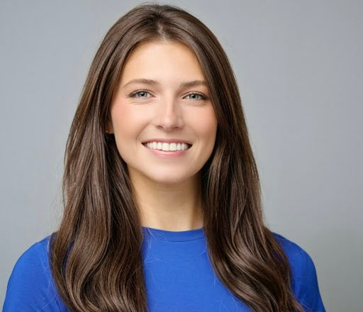 Professional headshot portrait of a smiling woman with brown hair wearing a blue top against gray background