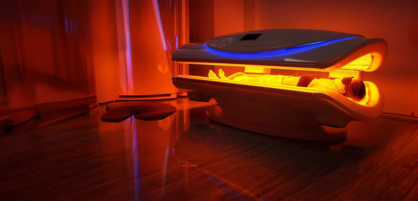 Infrared light therapy bed emitting warm orange glow in a dimly lit treatment room